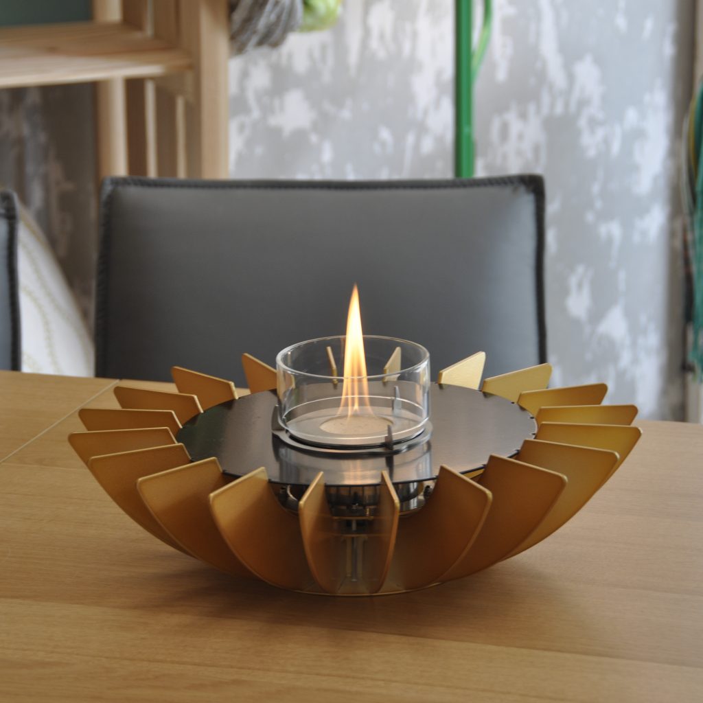 Cosmo bioethanol tabletop fireplace by GlammFire in a gold finish, featuring a modern, petal-like design with a central glass container showcasing the flame, perfect for indoor settings.
