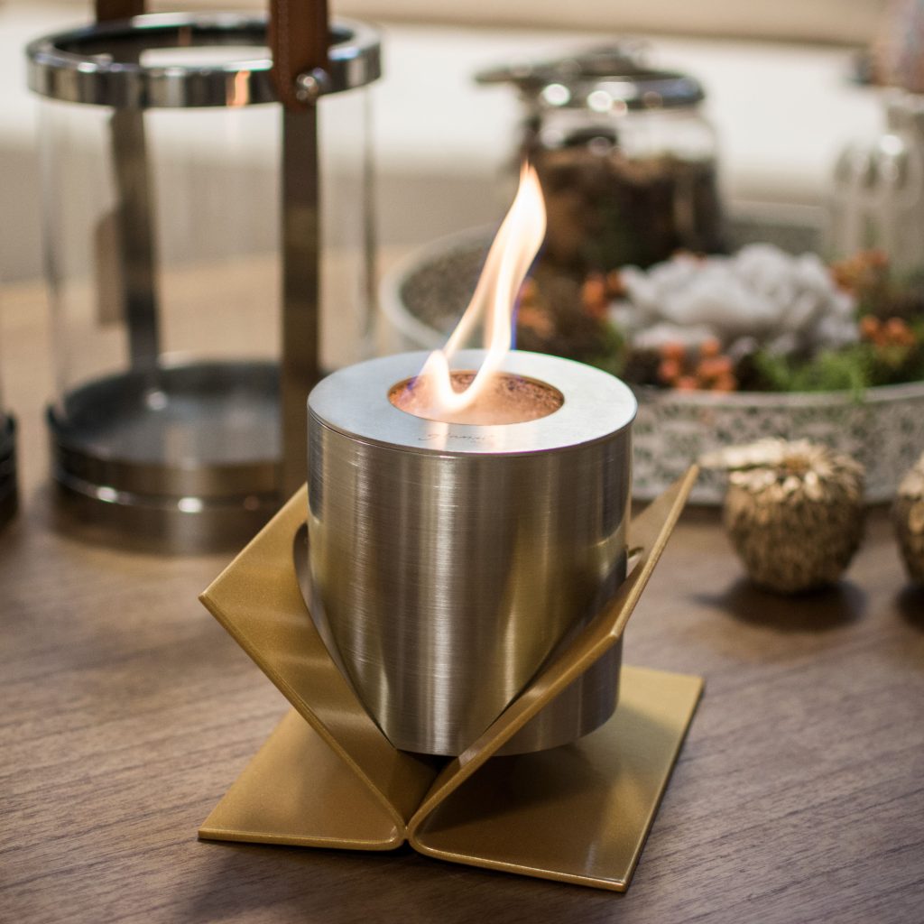 Kivo tabletop bioethanol fireplace by GlammFire with golden base, elegantly placed on a modern coffee table