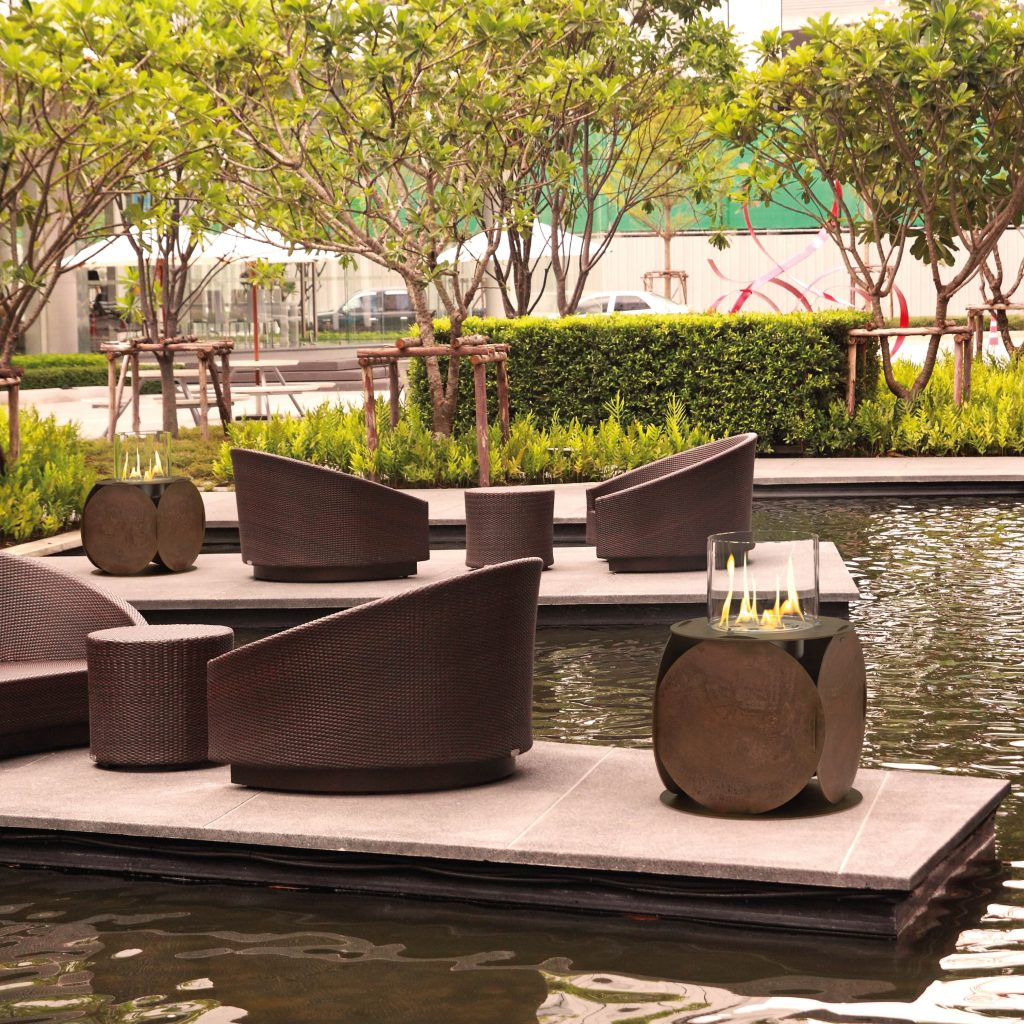 Lira bioethanol fire pit by GlammFire in an outdoor lounge setting by the water