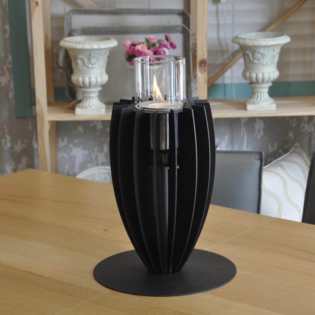 Wide view of the Tuli bioethanol tabletop fireplace by GlammFire in black, placed on a table, showing its full vertical design and elegant central flame.