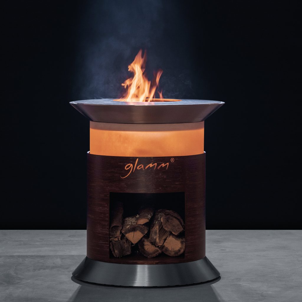 Close-up of Alba Grill by GlammFire, featuring a circular design with a fire pit and wood storage, perfect for outdoor cooking and entertaining.