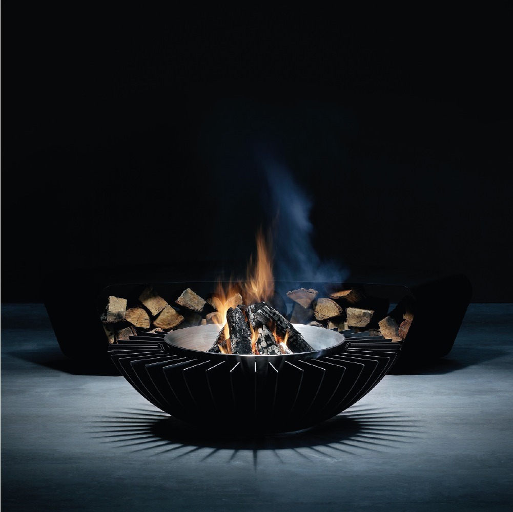 Studio image of the GlammFire Cosmo 13 fire pit with wood burning, featuring a modern black steel design and firewood storage, casting elegant shadows.