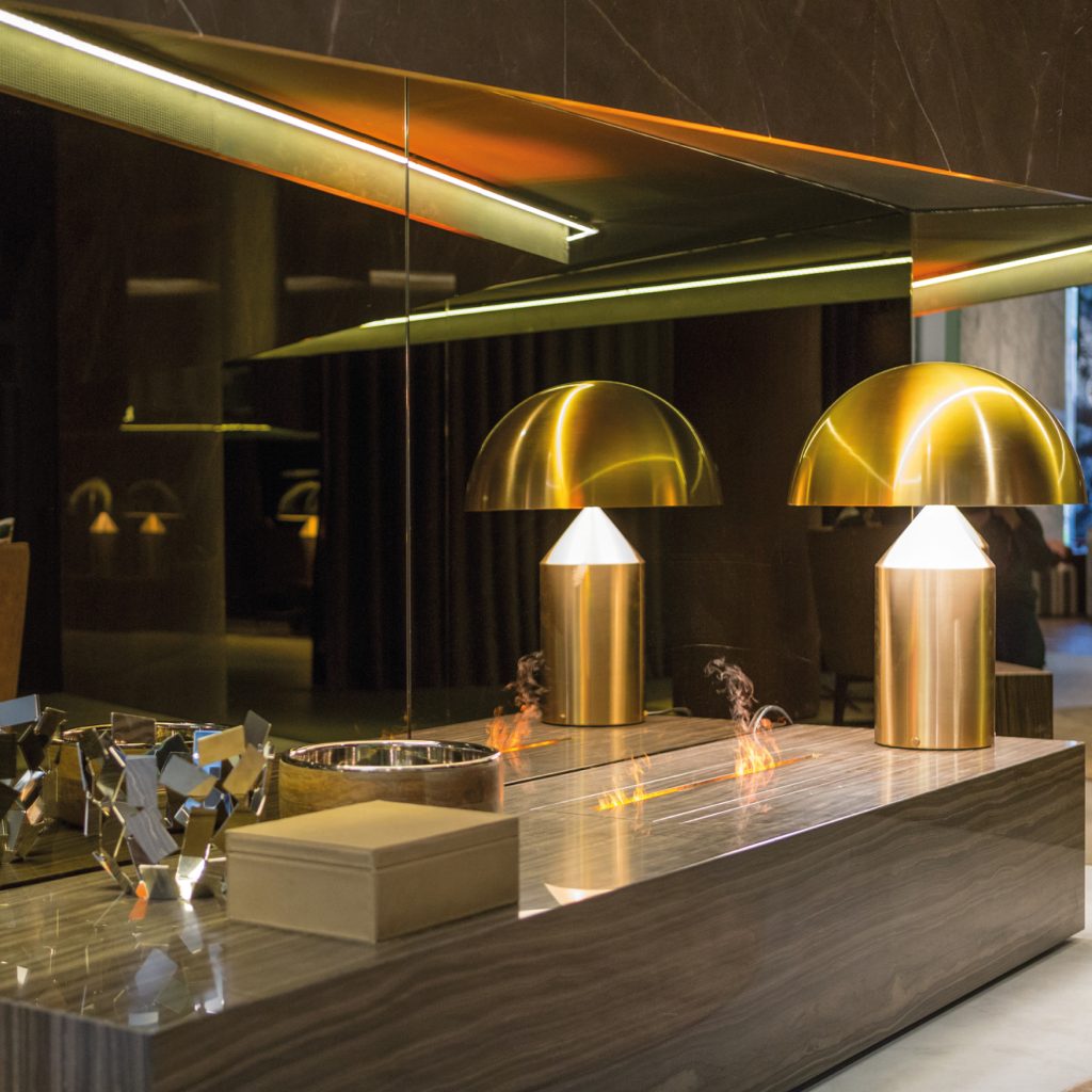 Gema electric fireplace by GlammFire in a luxurious modern interior setting, showcasing a sleek stone base with elegant, integrated flame elements.