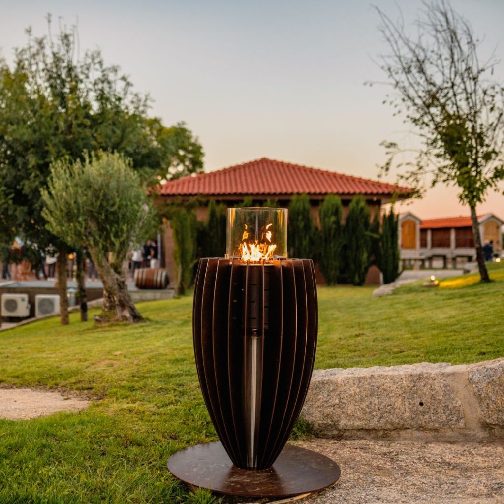 Fire pit Tuli gas, by GlammFire, outdoors with modern design in a natural landscape, ideal for outdoor heating.
