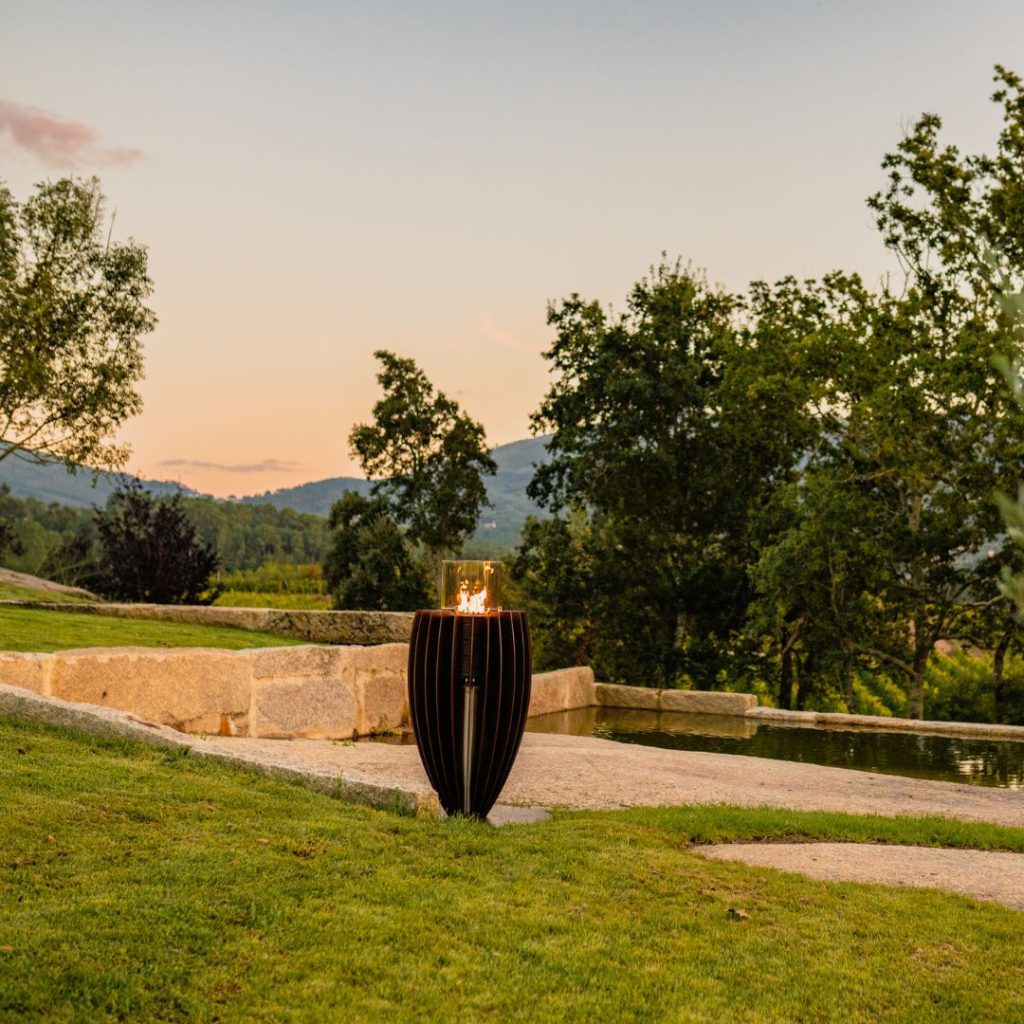 Fire pit Tuli gas, by GlammFire, outdoors with modern design in a natural landscape, ideal for outdoor heating.
