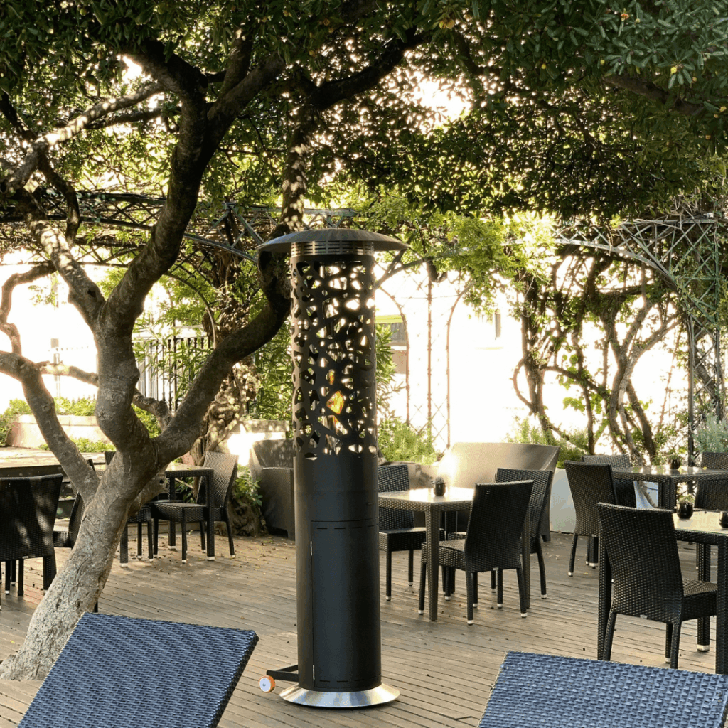 Tile Hyperion gas patio heater by GlammFire in an elegant outdoor hospitality setting surrounded by trees