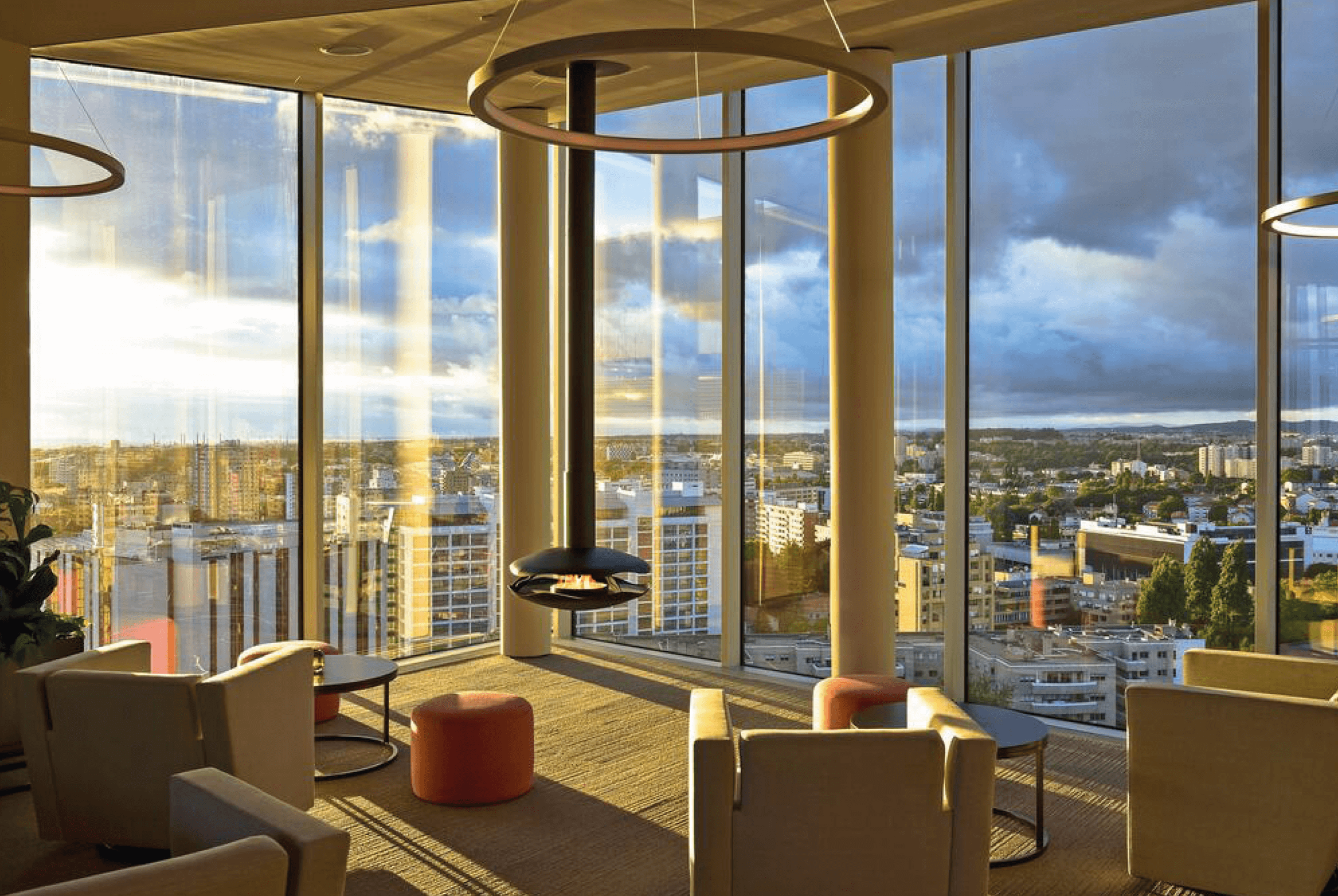 Perola suspended bioethanol fireplace in black lacquered steel located in a hotel with a view of buildings and sunset