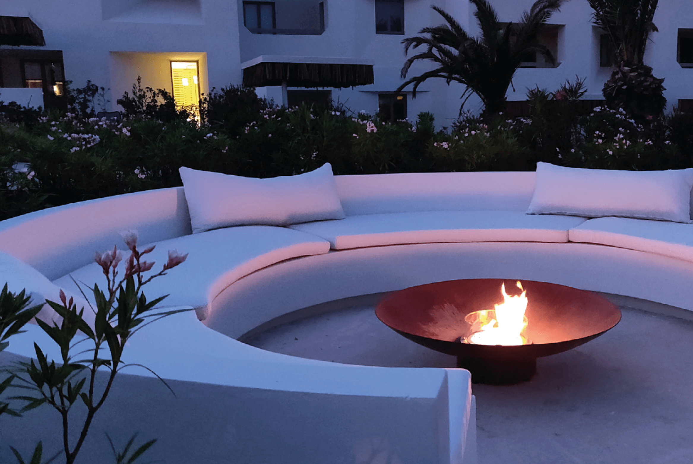 Bespoke fire pit centered in an outdoor space with stone benches and surrounded by lush vegetation