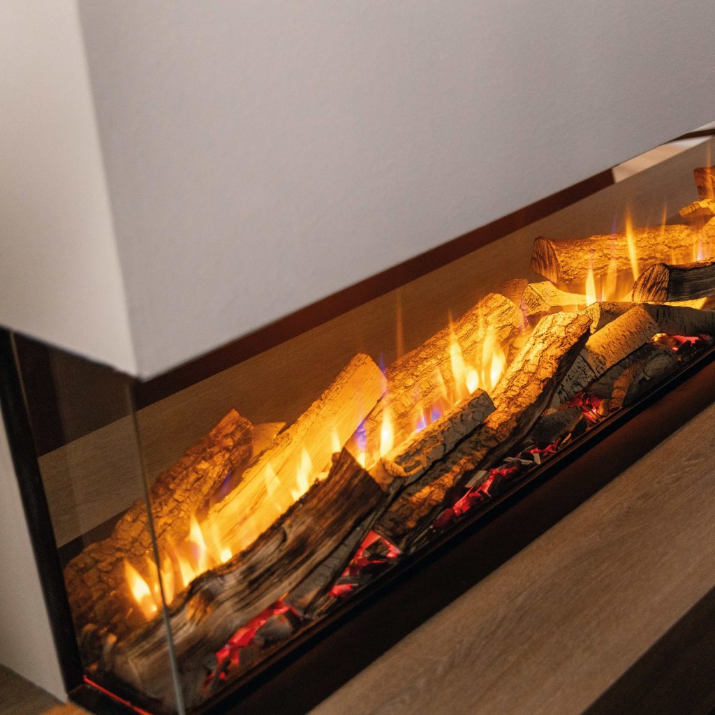 Close-up of the Spectrum electric fireplace by GlammFire, showcasing realistic flames and glowing log effects within a glass enclosure.