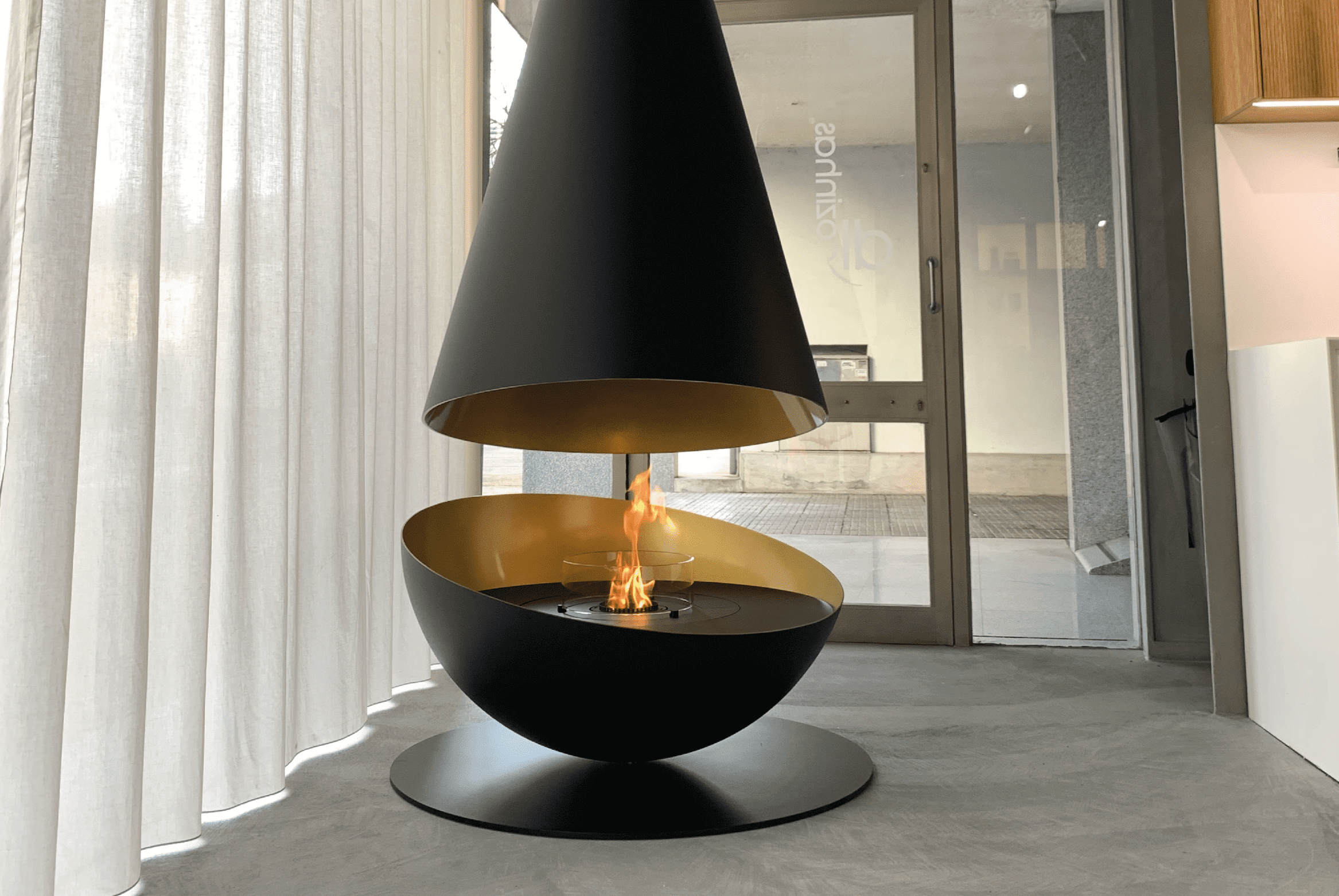 Thales suspended bioethanol fireplace by GlammFire with black and gold design in a modern interior setting
