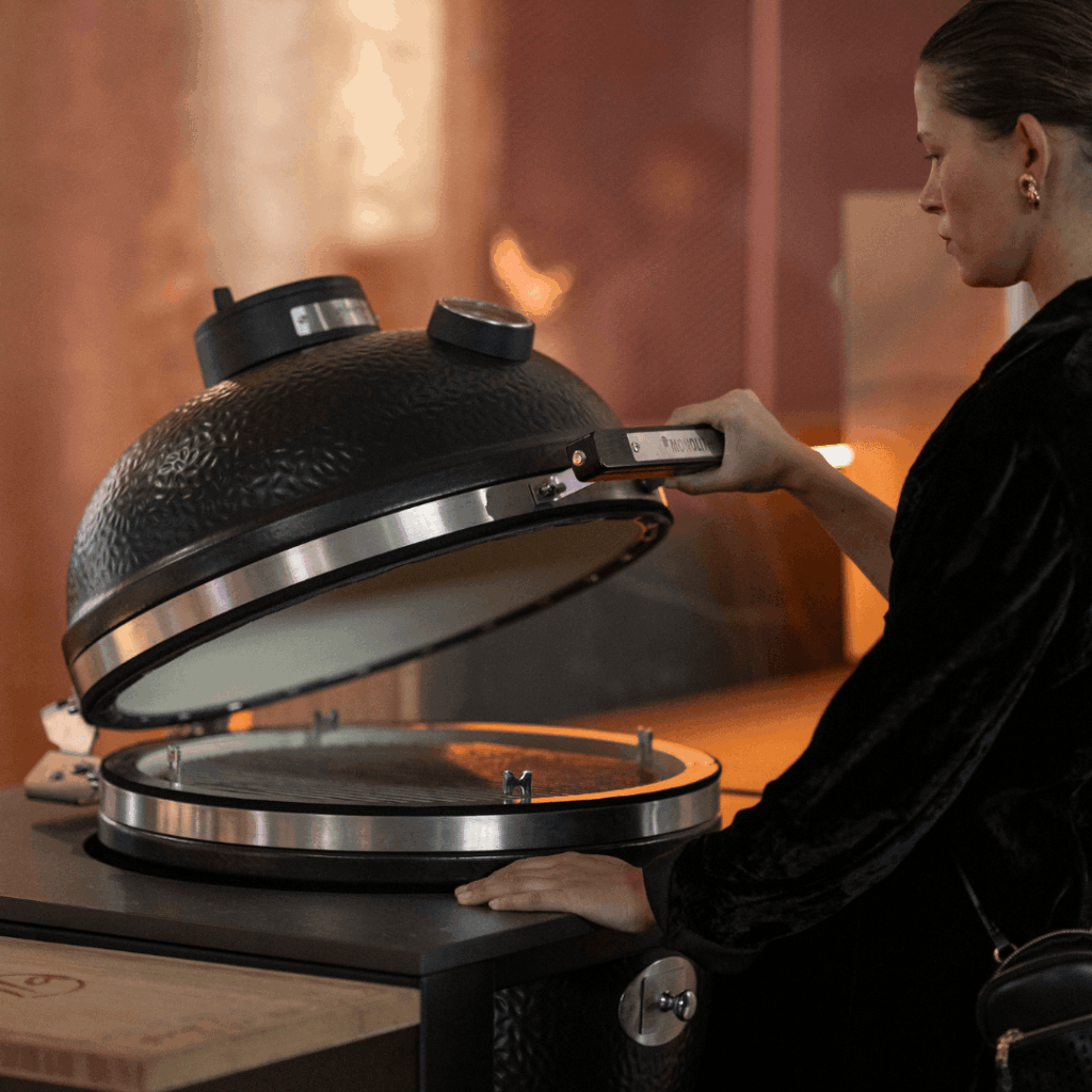 Person opening the kamado grill on Nero Plus outdoor kitchen by GlammFire