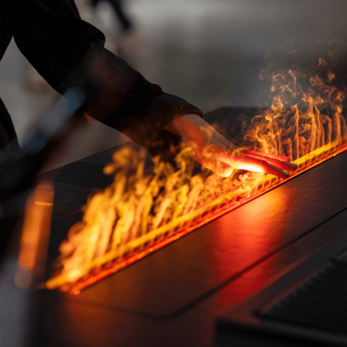 Hand interacting with GlammFire Glamm 3D Kit flame effect in a contemporary interior setting