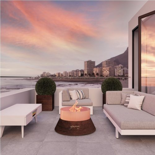 Alba Small gas fire pit in quartz set on a modern rooftop terrace at sunset, overlooking a coastal city skyline.