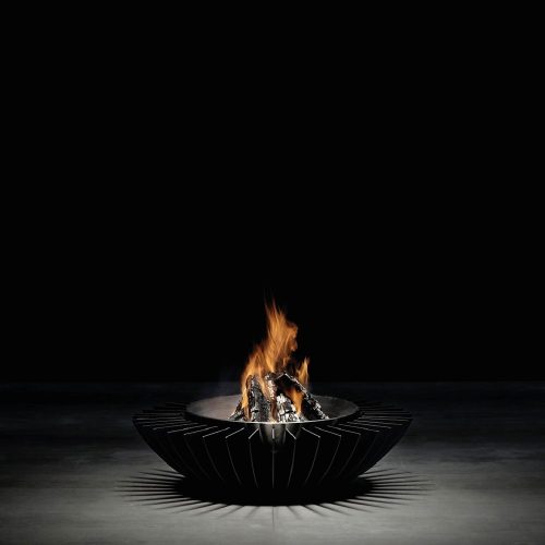 Minimalist studio shot of the GlammFire Cosmo 13 fire pit with wood burning, black steel design creating a modern aesthetic and casting dynamic shadows.