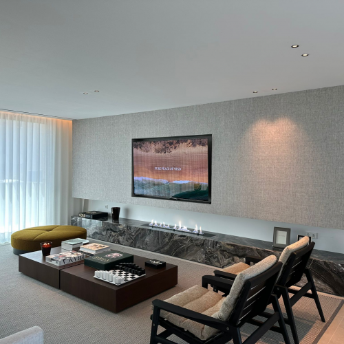 Lareira Fire Line EVOPlus da GlammFire integrada em sala ampla com painel em pedra natural.