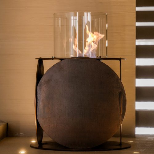 Lareira Lira a bioetanol da GlammFire em design circular em aço com vidro protetor.