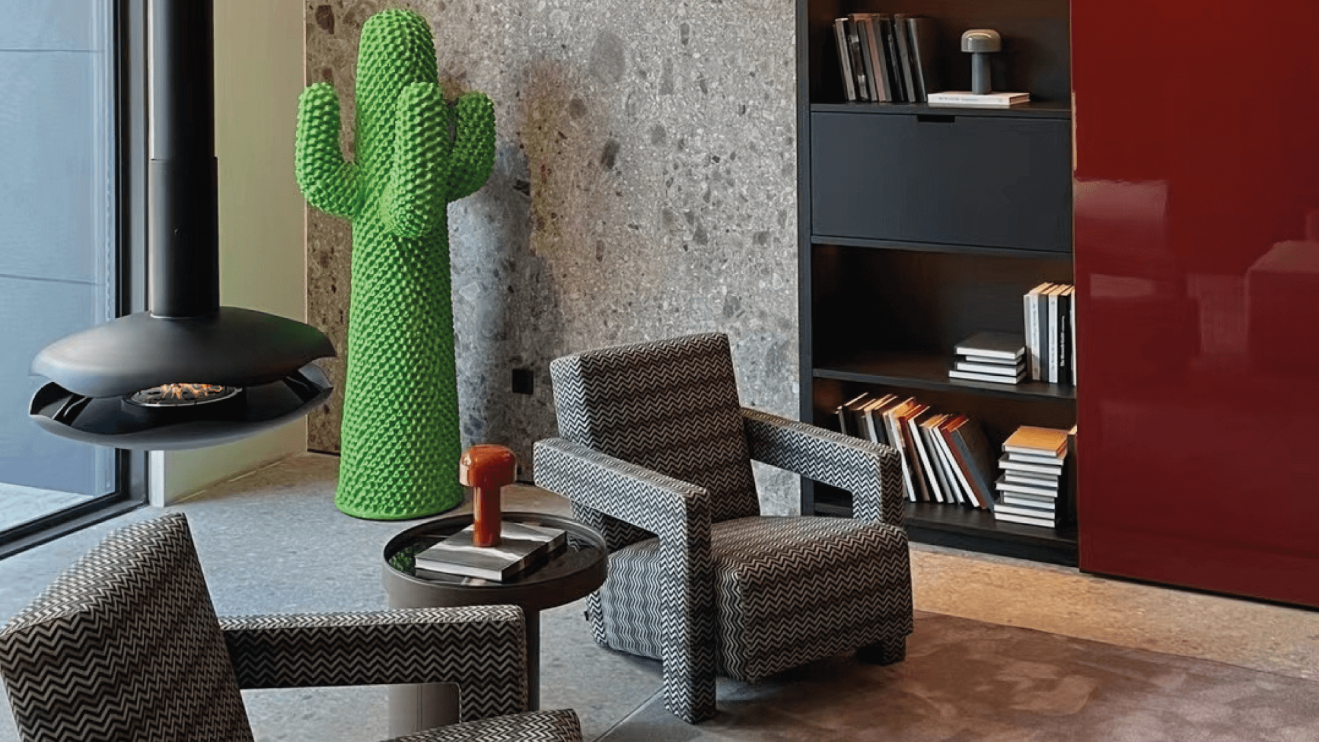 Perola suspended bioethanol fireplace with black lacquer finish and marine-inspired design in a modern living room with chairs and bookshelves