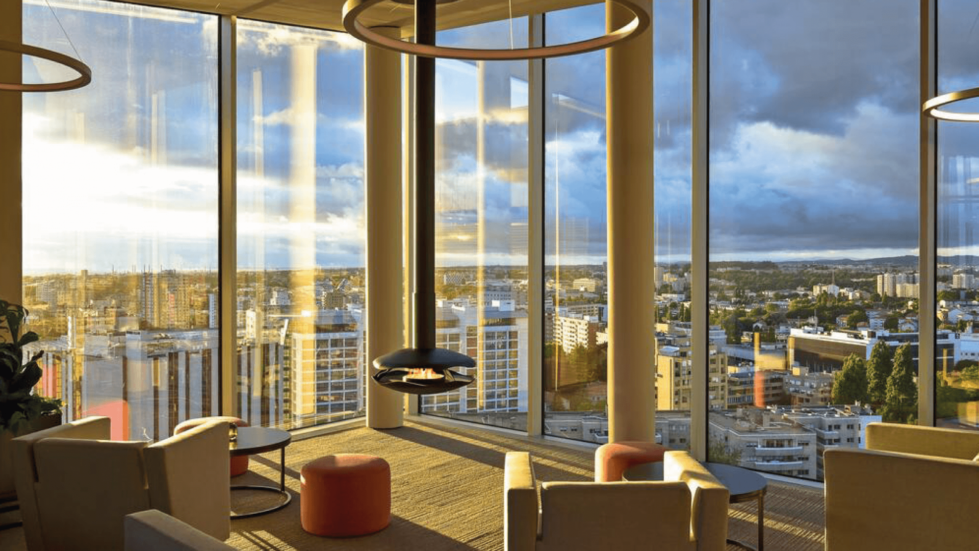Perola suspended bioethanol fireplace in black lacquered steel located in a hotel with a view of buildings and sunset