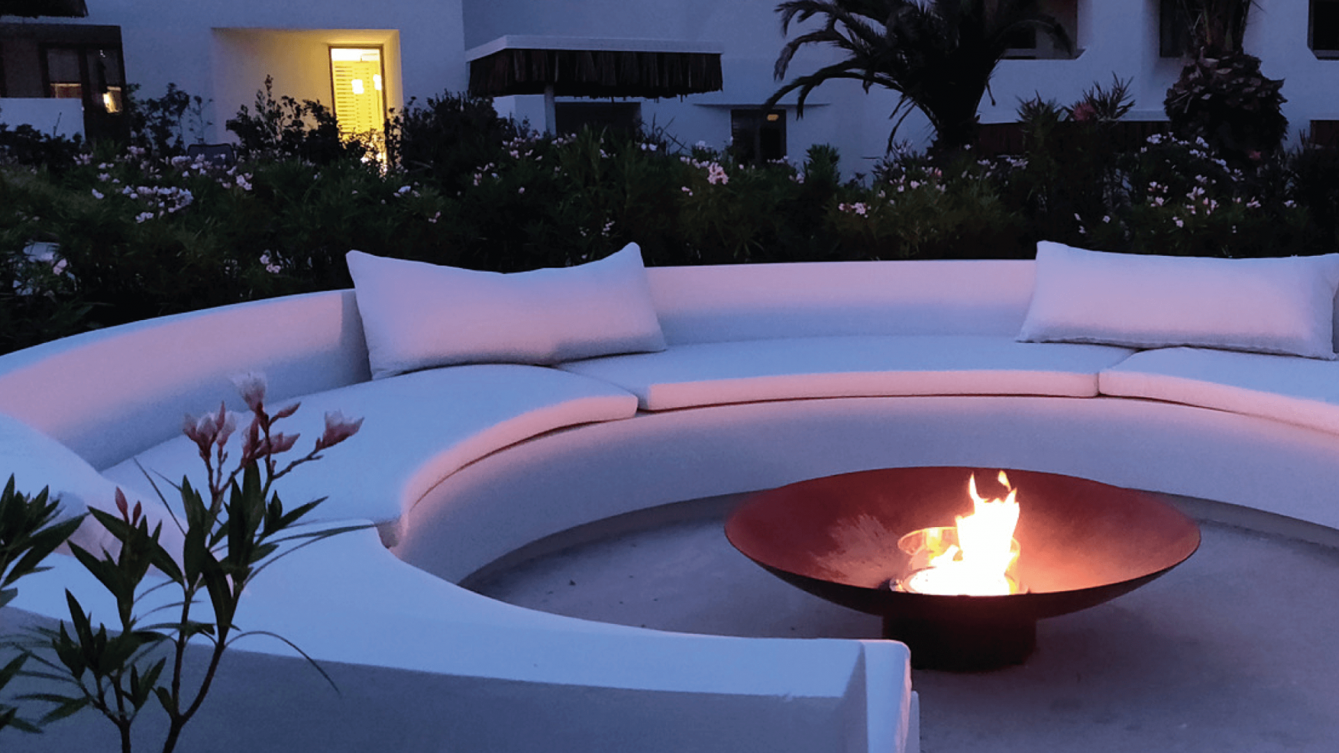 Bespoke fire pit centered in an outdoor space with stone benches and surrounded by lush vegetation