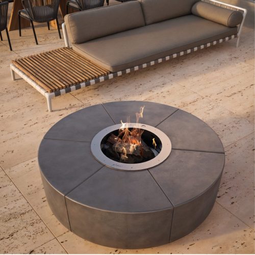 The Zarzuela fire pit with a round cement silhouette on a luxury patio, next to a lounger and sofa.